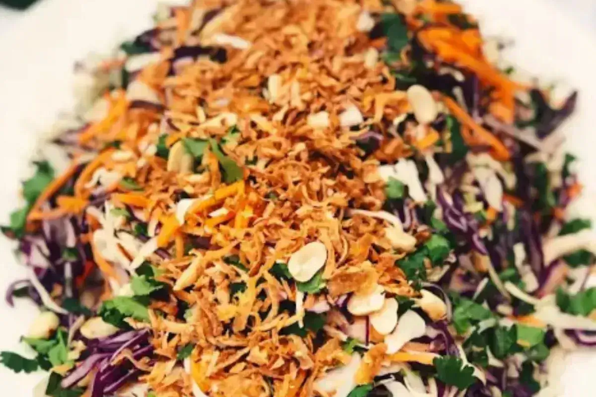 A bowl of vibrant chicken and cabbage salad with fresh ingredients.