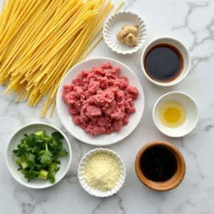  A flat lay of ingredients for Mongolian Ground Beef Noodles, including noodles, beef, soy sauce, garlic, and ginger.